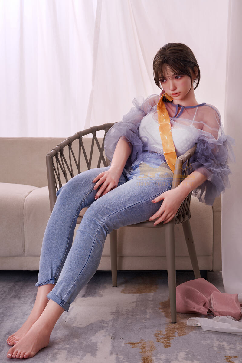 Real sex doll lehnt entspannt auf einem Stuhl, Licht fällt weich auf ihren Körper