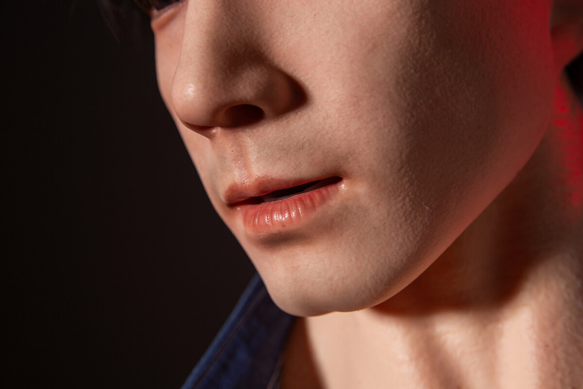 Detailaufnahme von Lippen und Gesicht einer realistischen Qita Doll im roten Licht