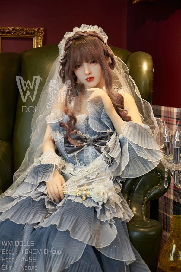 WM Doll Felicia in einem eleganten blauen Kleid, sitzt anmutig auf einem Vintage-Sessel
