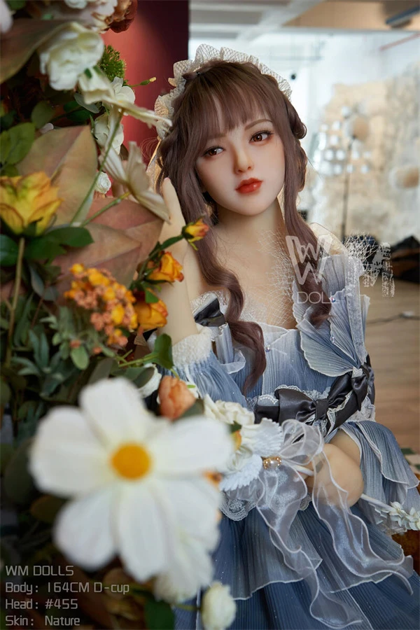 Künstlerische Aufnahme der eleganten Love doll zwischen blühenden Blumen