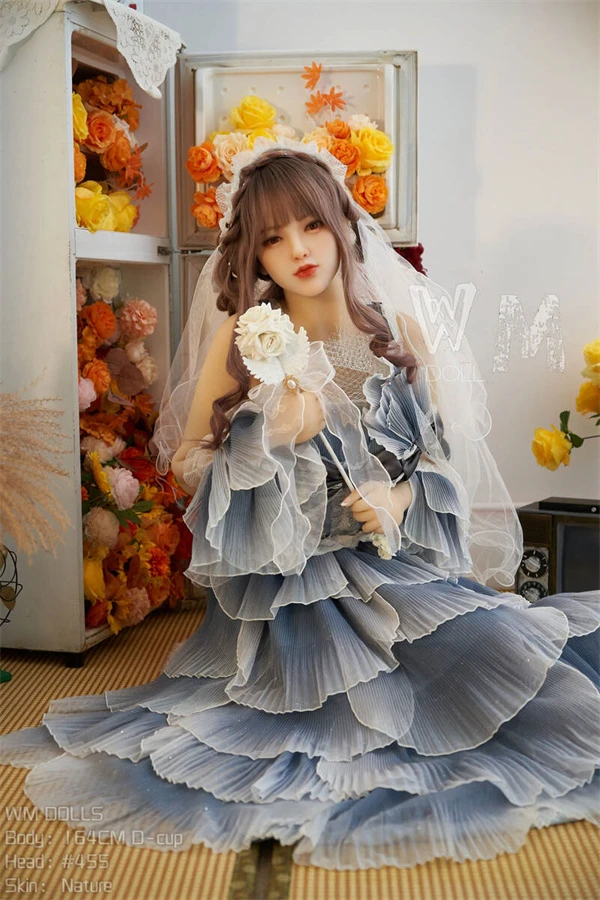 Real doll im hellen Studio mit blauer Rüschenschicht und Blumen